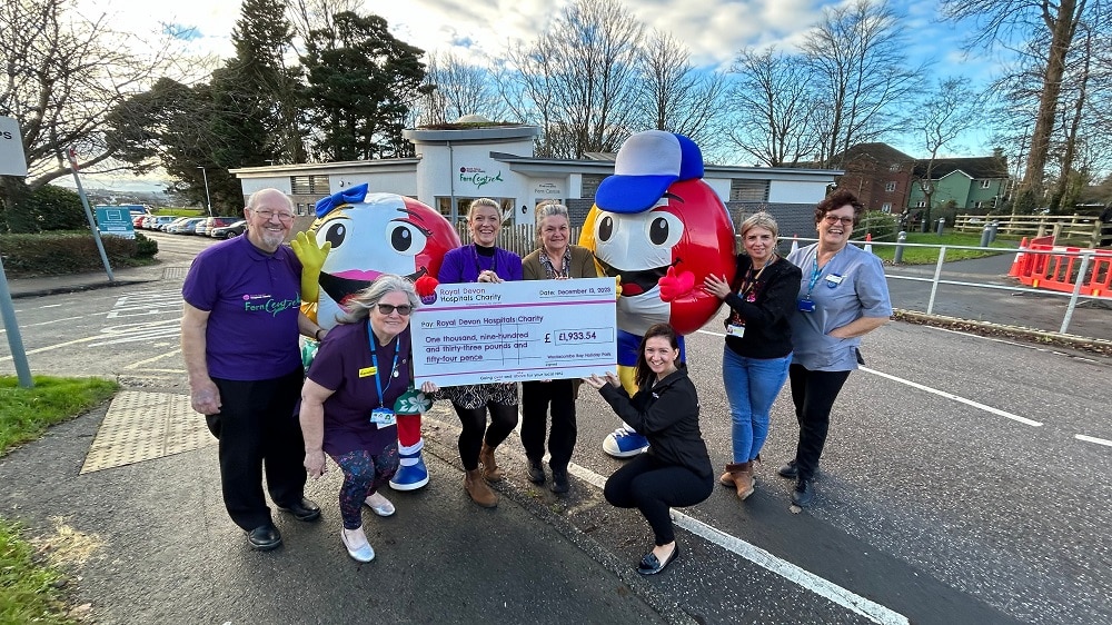 Woolacombe Bay Holiday Parks Head of Entertainment and HR, Kate Glover, and mascots Billy and Betty Beachball, present the fundraising cheque to Royal Devon Hospitals Charity community fundraiser Kate Constable and Fern Centre staff and volunteers.