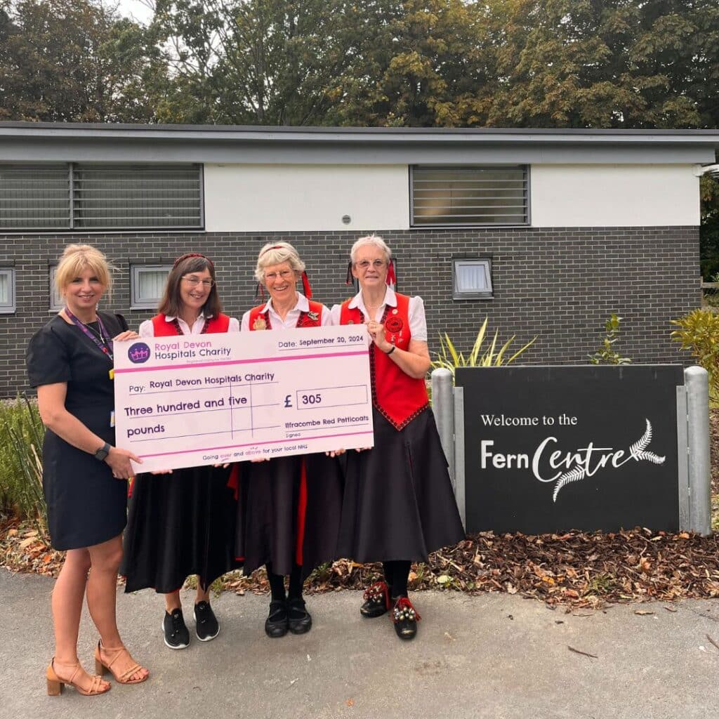 Janet Ellis and members of The Ilfracombe Red Petticoats present the groups’ fundraising cheque to Fern Centre manager Tara Jones. Pic: Royal Devon Hospitals Charity