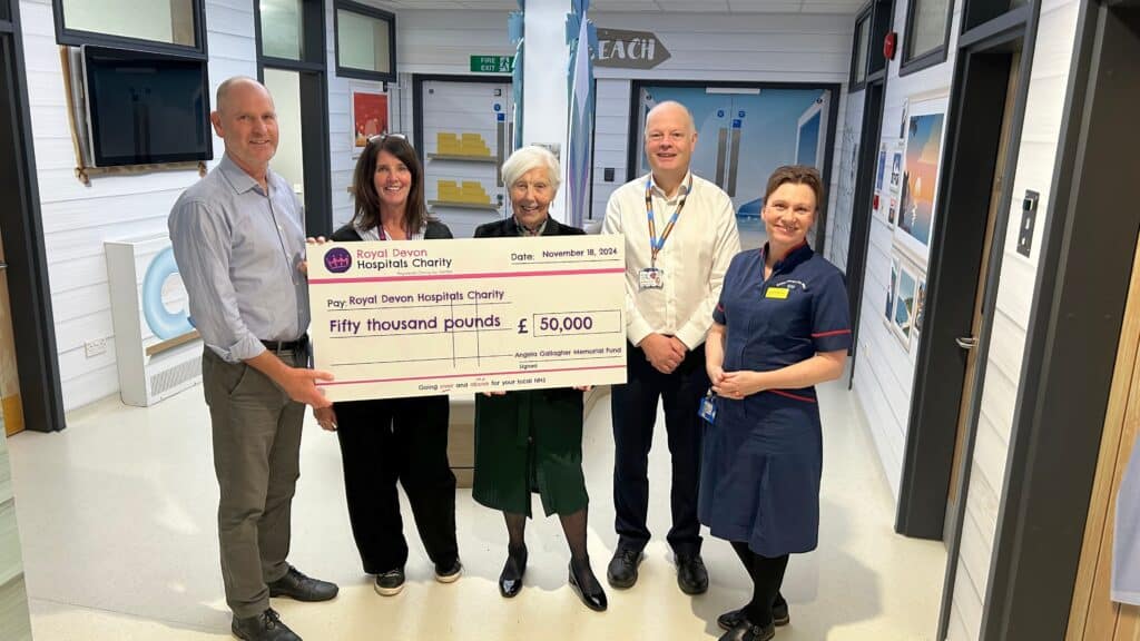 Di Moss Angela Gallagher Memorial Fund trustee presents the fundraising cheque to Catherine Manlow, Clinical Nurse Manager for Paediatrics; Richard Tomlinson, Consultant Paediatrician; Debbie Allen, Royal Devon Hospitals Charity community fundraiser; and Sam Higginson, Royal Devon University Healthcare NHS Foundation Trust chief executive.