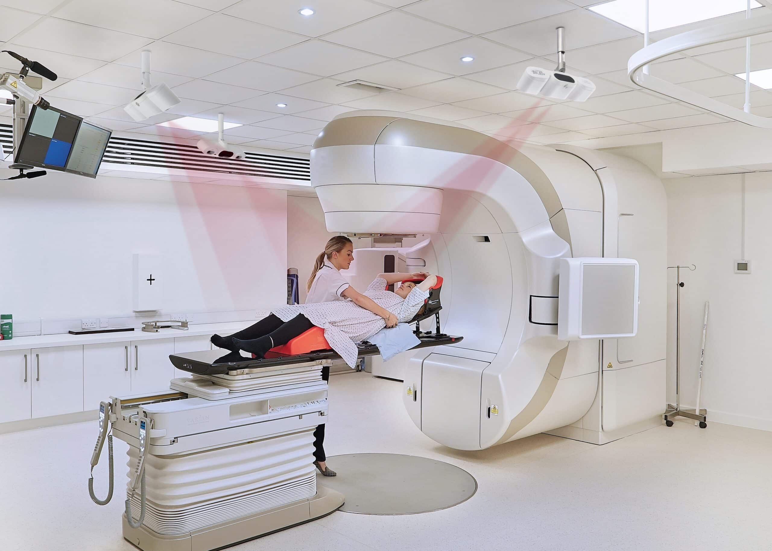 SGRT uses ceiling cameras to scan and monitor the patient’s body during treatment. The red beams in this image demonstrate the optical camera monitoring, although they are not visible in reality.